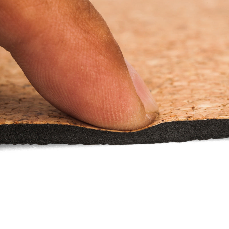 Close-up of a hand pressing the cork yoga mat surface.